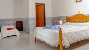 Un dormitorio con una cama, una puerta de madera, una mesita de noche y un tocador.