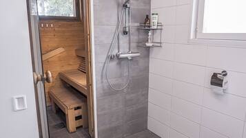 A bathroom with a shower, a toilet, and a bench.
