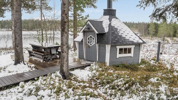 A cabin with a chimney, a deck, and a small window.