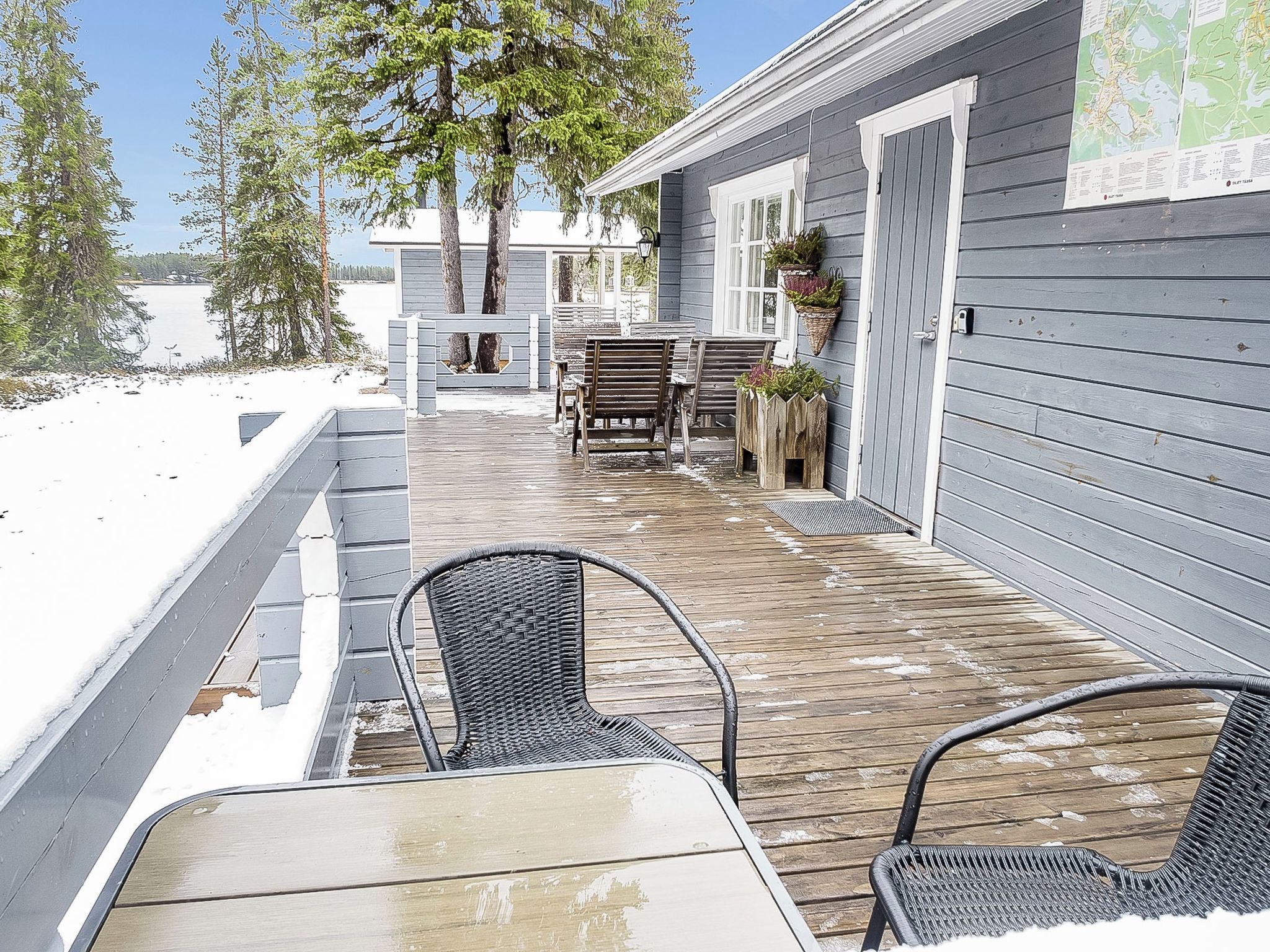 Une terrasse en bois avec des sièges extérieurs, un espace abrité et une vue sur un lac.