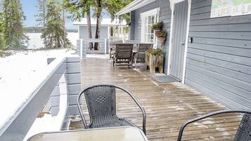 A wooden deck with outdoor seating, a covered area, and a view of a lake.