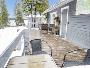 A wooden deck with outdoor seating, a covered area, and a view of a lake. - Kuusela by Interhome (Kuusamo)