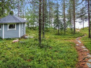A cabin with a small porch and a stone pathway leading through a forest.