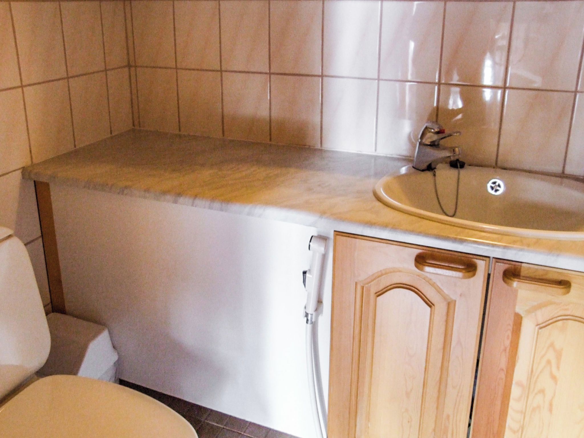 Et badeværelse med toilet, håndvask og træskabe.