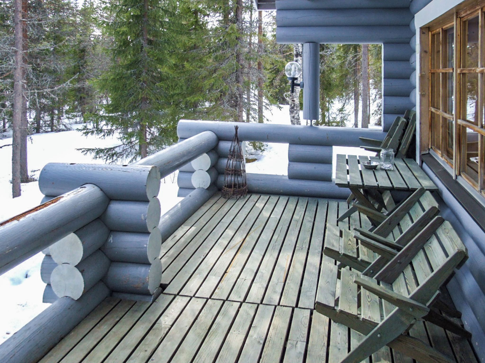 Une terrasse en bois avec un banc et une table, entourée de murs en rondins de bois.