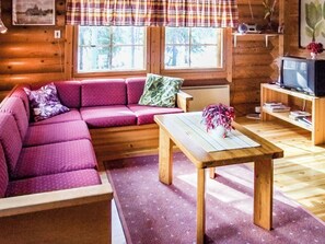A cozy cabin interior with a wooden sofa, a small table, and a television.