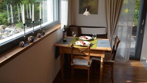A dining area with a wooden table, chairs, and a view of greenery outside. - Bolzli-Hus by Interhome (Blankenburg)
