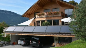 A modern two-story house with a sloped roof, large windows, and a covered garage with two cars parked inside. - Bolzli-Hus by Interhome (Blankenburg)