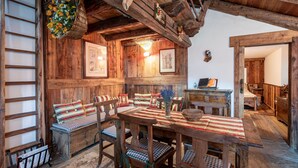 Ein rustikaler Holzinnenraum mit einem Holztisch, Bänken und einer Leiter.