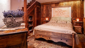 Ein rustikales Schlafzimmer mit einem hölzernen Bett, einer Treppe und einem an der Wand befestigten Gemälde.
