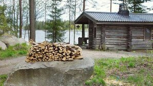 Eine rustikale Holzhütte am See mit einem Holzstapel davor.