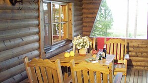 Ein Holzblockhaus-Innenraum mit Esstisch, Stühlen, einem Fenster und einer Laterne.