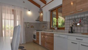 Une cuisine moderne avec un dosseret carrelé, des armoires en bois, un four encastré et un lave-vaisselle.