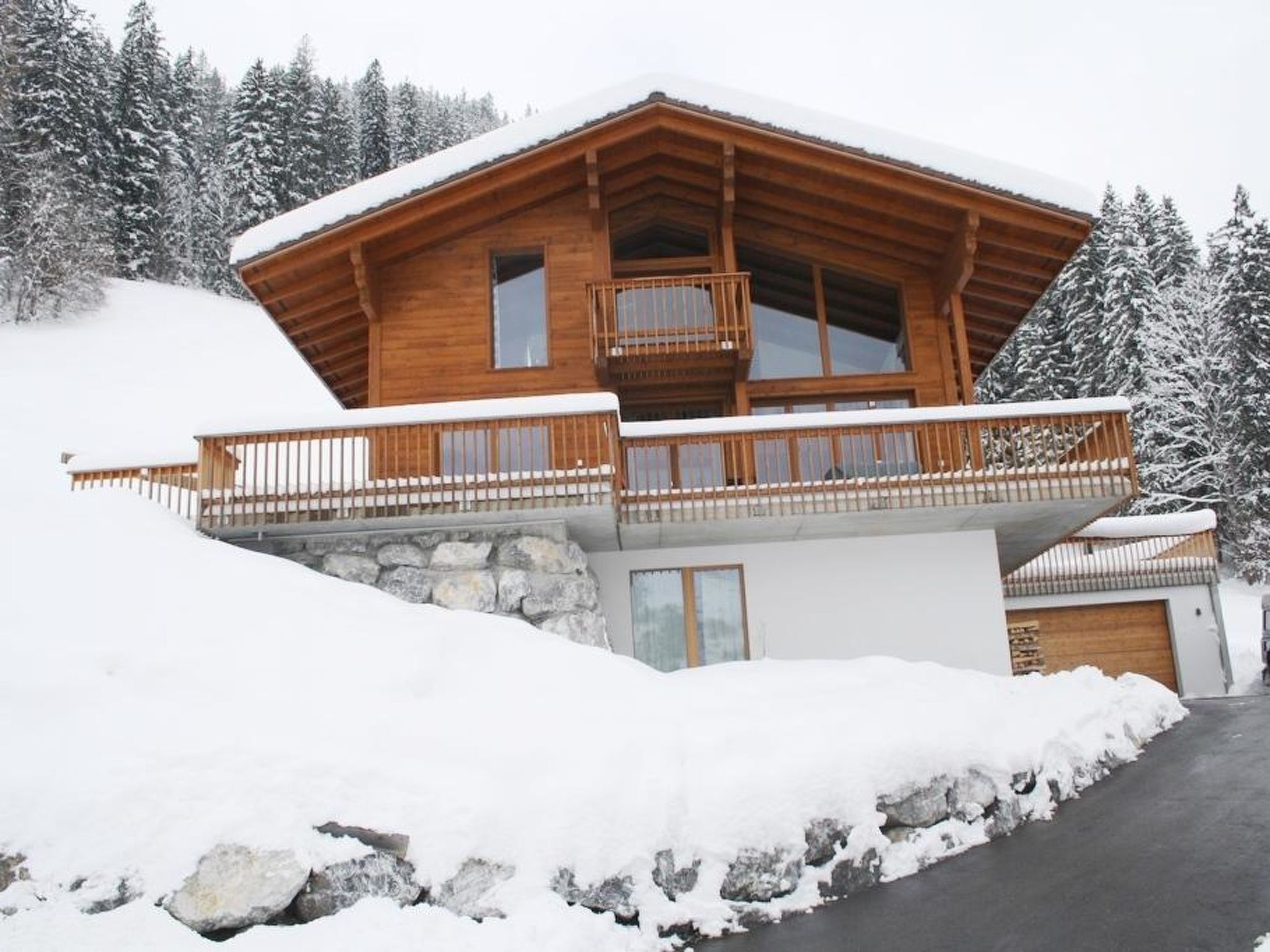 Una baita di legno con un balcone, sullo sfondo di un paesaggio innevato.