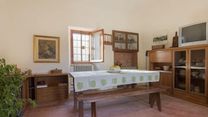 Un coin repas avec une table dressée pour deux personnes, un radiateur, des meubles en bois et un téléviseur.