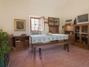 Un comedor con una mesa para dos, un radiador, armarios de madera y un televisor.
