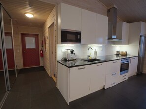 Een koelkast, een magnetron, een vaatwasser, kookgerei, borden en bestek