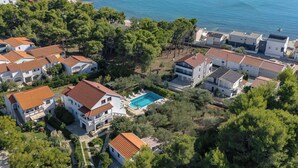 Zona residencial costera con casas, piscina y playa.