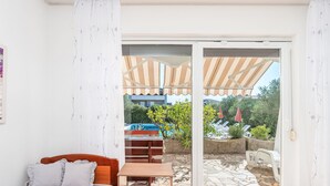 Una habitación con cama, una mesita y un ventanal corredera que da a un área exterior con piscina y sombrillas.