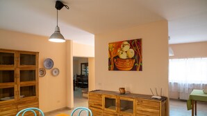 A dining area with a wooden table and chairs, a cabinet with drawers, and a painting of fruit on the wall. - Vacation home Breda by Interhome (Città Sant'Angelo)