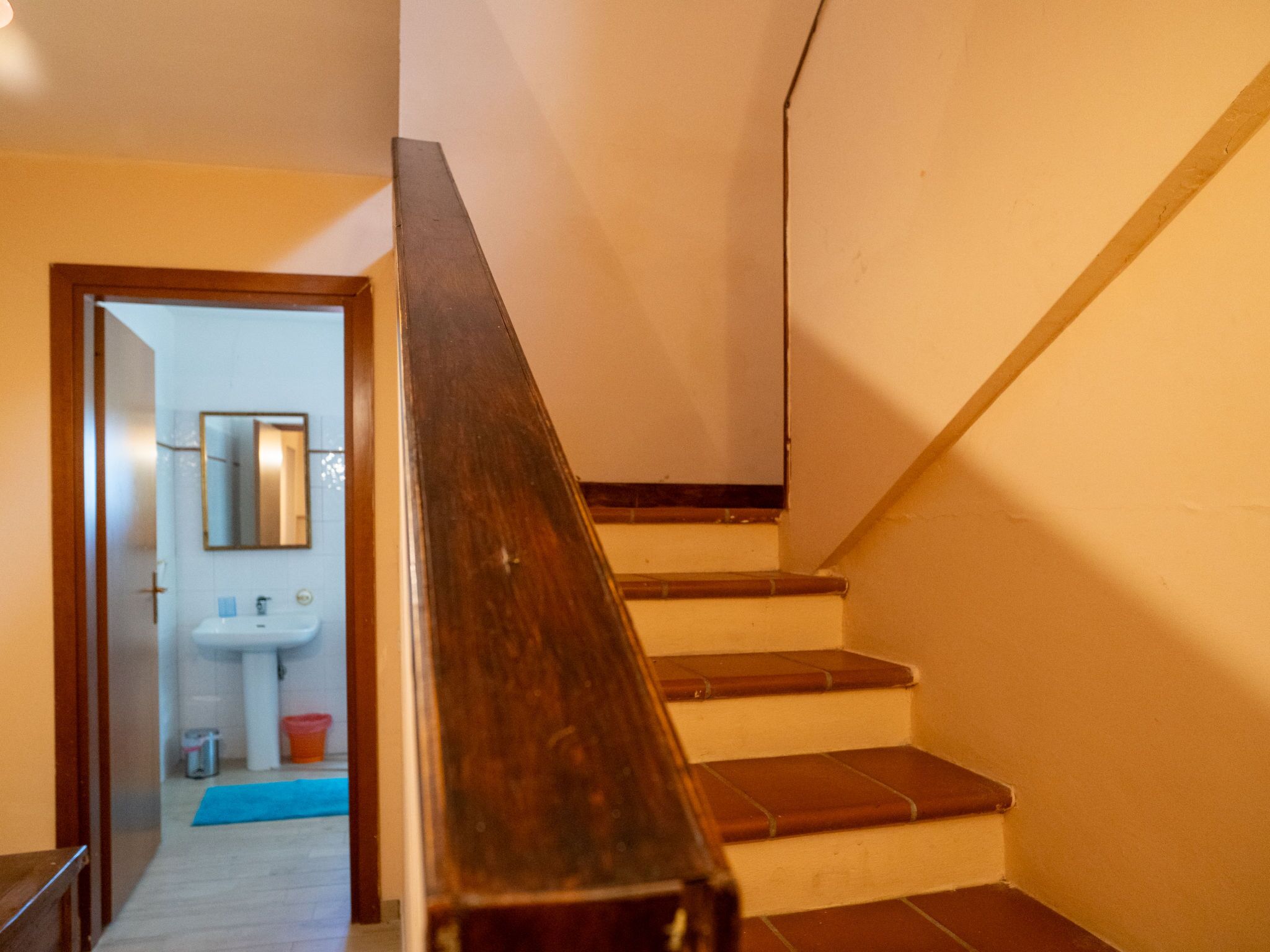 Una escalera de madera con barandilla que conduce a un piso superior.
