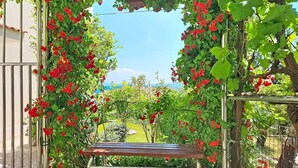 An outdoor seating area with a bench, surrounded by a metal gate and a flowering arbor.