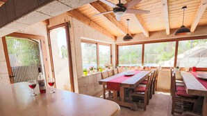 A wooden interior with a dining area, large windows, and a ceiling fan.
