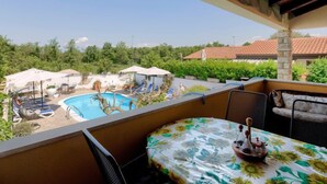 Un balcon avec piscine, un espace salon extérieur et une vue sur un quartier résidentiel.