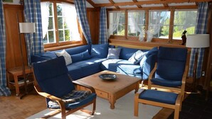 Een gezellige kamer met een houten bank, een sofa en een tafel.
