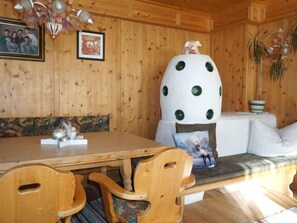 Ein gemütliches Holzhaus-Interieur mit einem Holzesstisch, Stühlen, einer Bank und einer Couch.