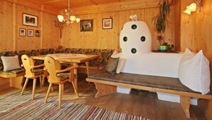 Een gezellig houten vakantiehuisje met een eethoek, een bank en een grote plant.