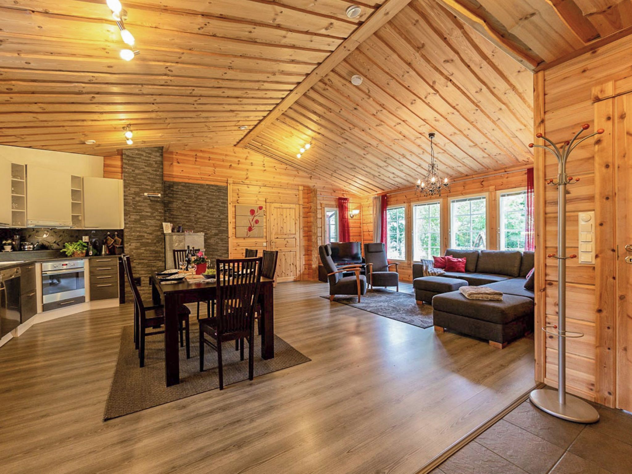 A spacious wooden cabin interior with a dining area, kitchen, and living room.