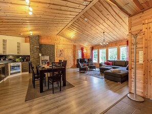Un intérieur de chalet en bois spacieux, comprenant un coin repas, une cuisine et un salon.