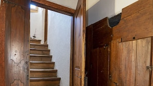 Eine Holztreppe führt zu einem Raum mit weißer Wand und Holztür.