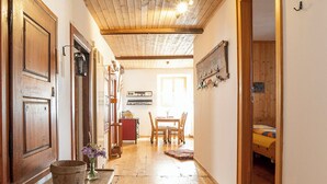 Ein Holzboden führt in einen Flur mit Decke, einem Essbereich mit Stühlen und Tisch sowie einem Bett im Hintergrund.