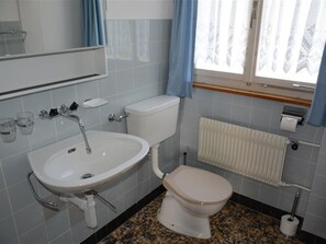 Ein Badezimmer mit Waschbecken, Toilette und einem Fenster mit Vorhängen.