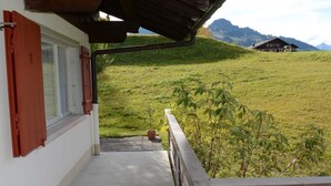 Un balcón con vistas a una ladera verde y una montaña al fondo.