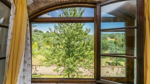 Una habitación con un amplio ventanal que ofrece vistas a un árbol y un muro de ladrillo.