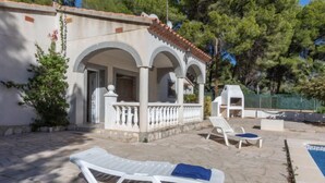 A villa with a covered patio, outdoor seating, and a swimming pool.