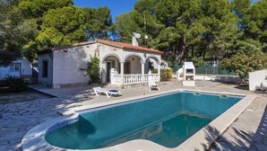 A villa with a swimming pool, outdoor seating, and a garden.