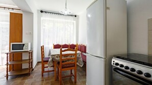 A compact kitchen with a refrigerator, microwave, and stove. - Margaret by Interhome (Balatonfenyves)