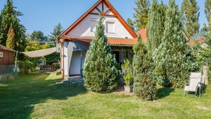 A house with a red-tiled roof, a white exterior, and a covered porch. There are several evergreen trees in the yard. - Margaret by Interhome (Balatonfenyves)