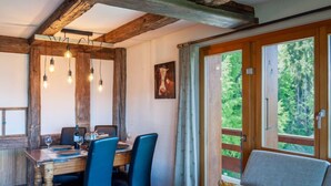 A dining area with a wooden table, blue chairs, and hanging light fixtures. - Quille du Diable 44 by Interhome (Nendaz)