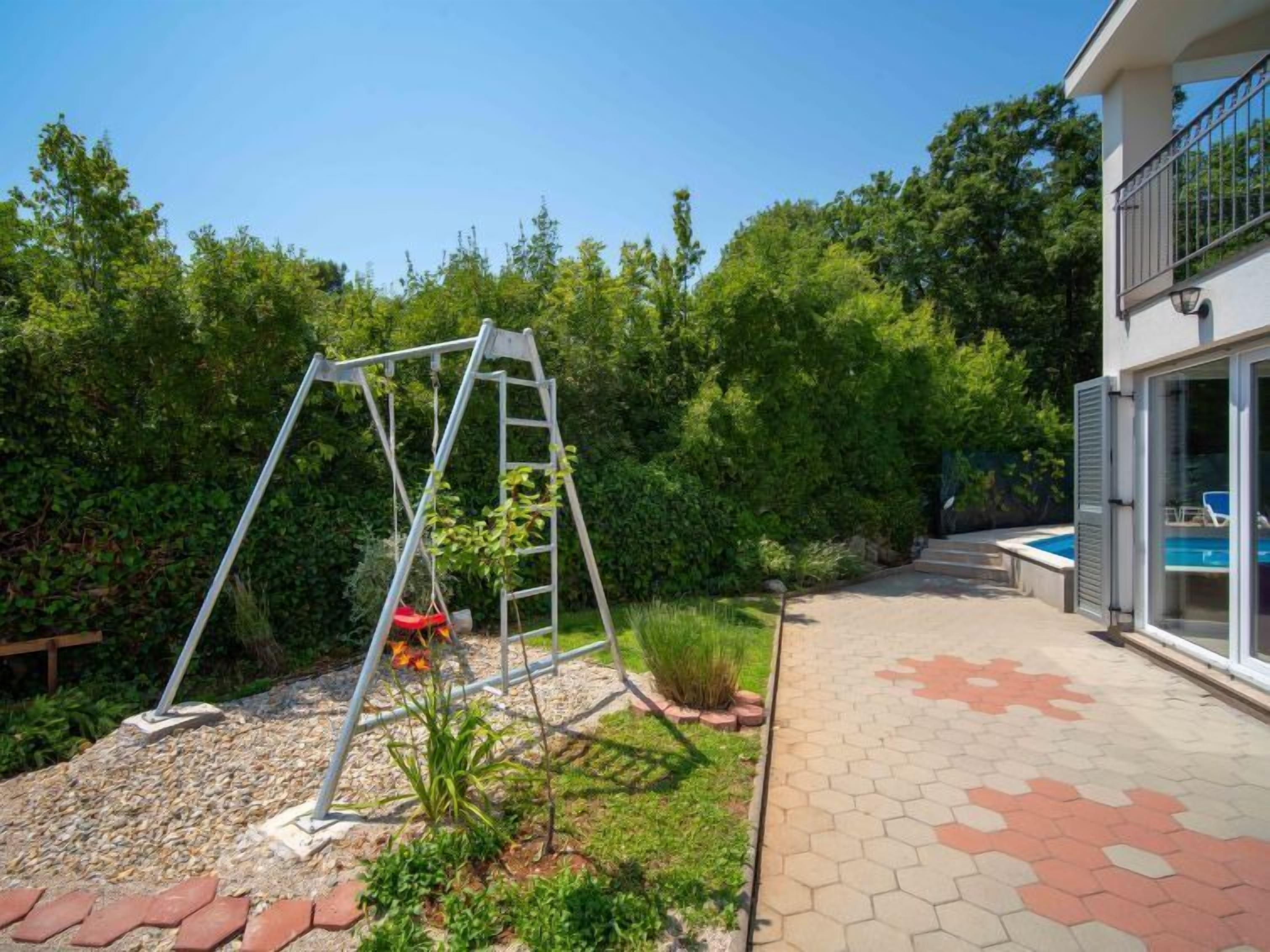 Un jardin avec une balançoire, un petit potager et un espace piscine.