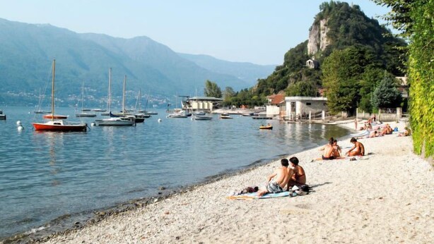 A beach with boats, people sunbathing, and a mountain in the background. - Rossella by Interhome (Castelveccana)