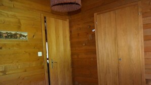 Een houten kamer met een bed, een deur en een aan de muur hangend schilderij.