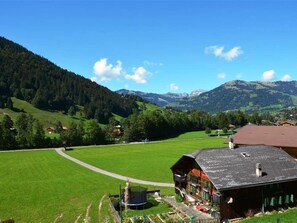 Ländliche Berglandschaft mit einem Holzhäuschen, das eine große Veranda und Blick auf die umliegenden grünen Felder und Hügel bietet.