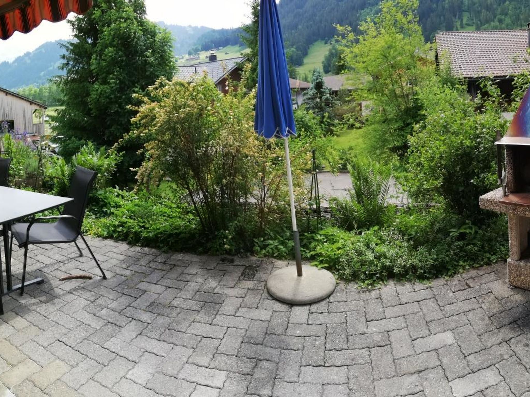 Une terrasse avec une table et des chaises, entourée de verdure et offrant une vue sur un village.