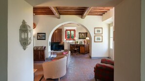 A cozy living room with a television, a dining area with a table and chairs, and a red armchair. - La Forra by Interhome (Vicchio)