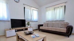 A modern living room with a flat-screen TV, a wooden coffee table, a beige sofa, and a dining table. - Bili dvori by Interhome (Trilj)
